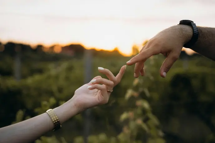 Two people reaching out their hands to touch each other